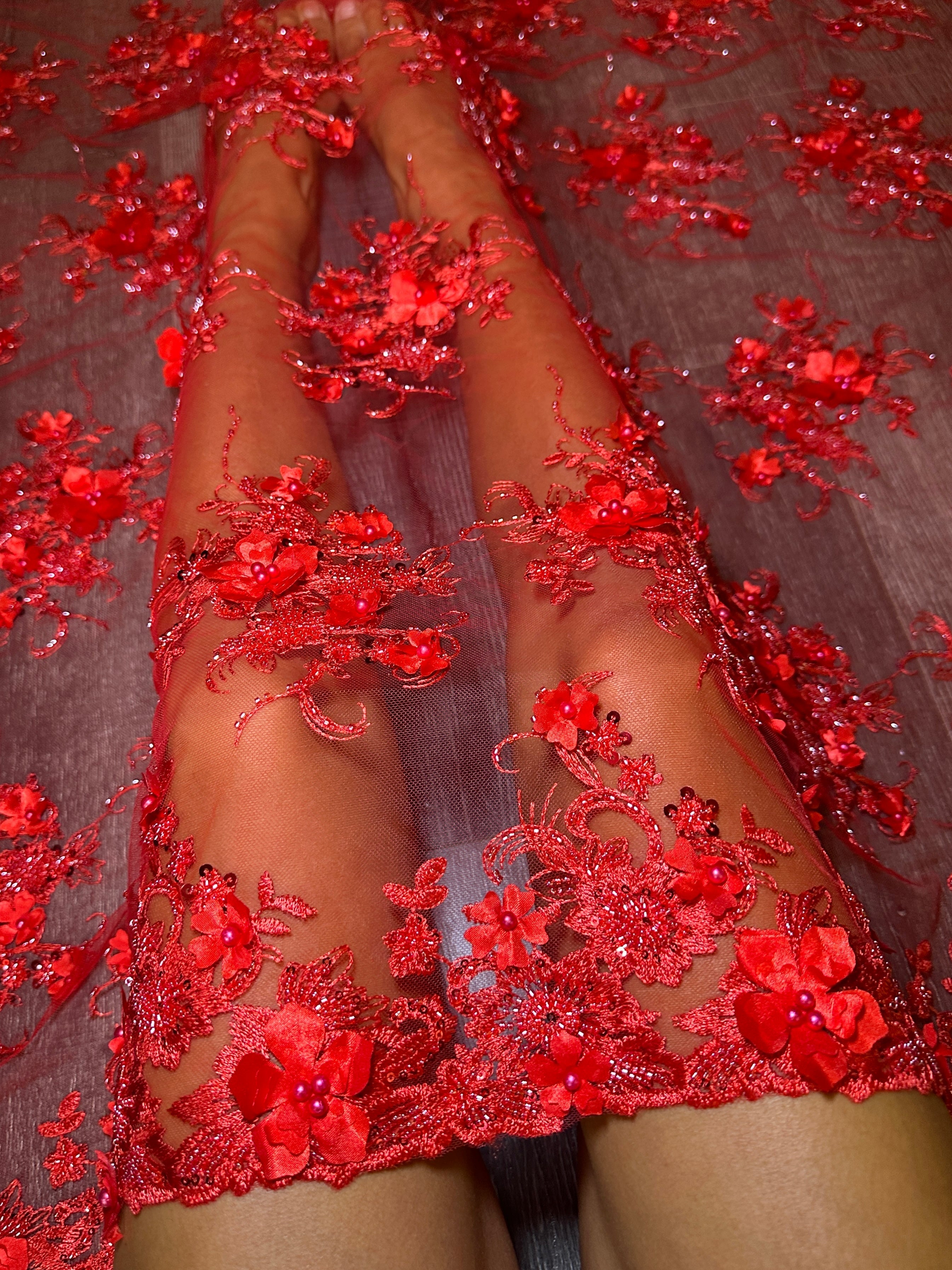 Red floral lace garment on a person against a dark background