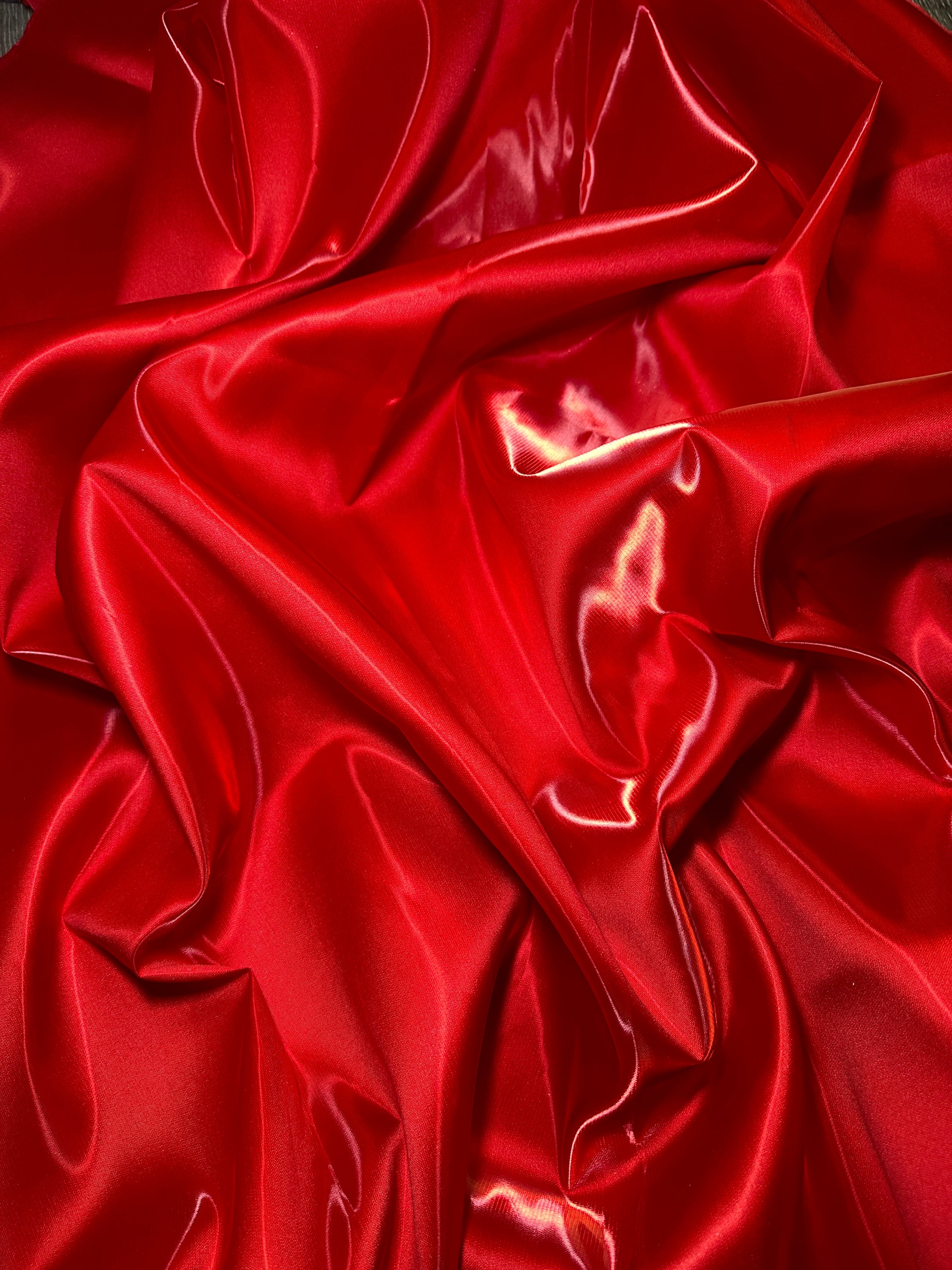 close up look of red luxury satin fabric with folds 