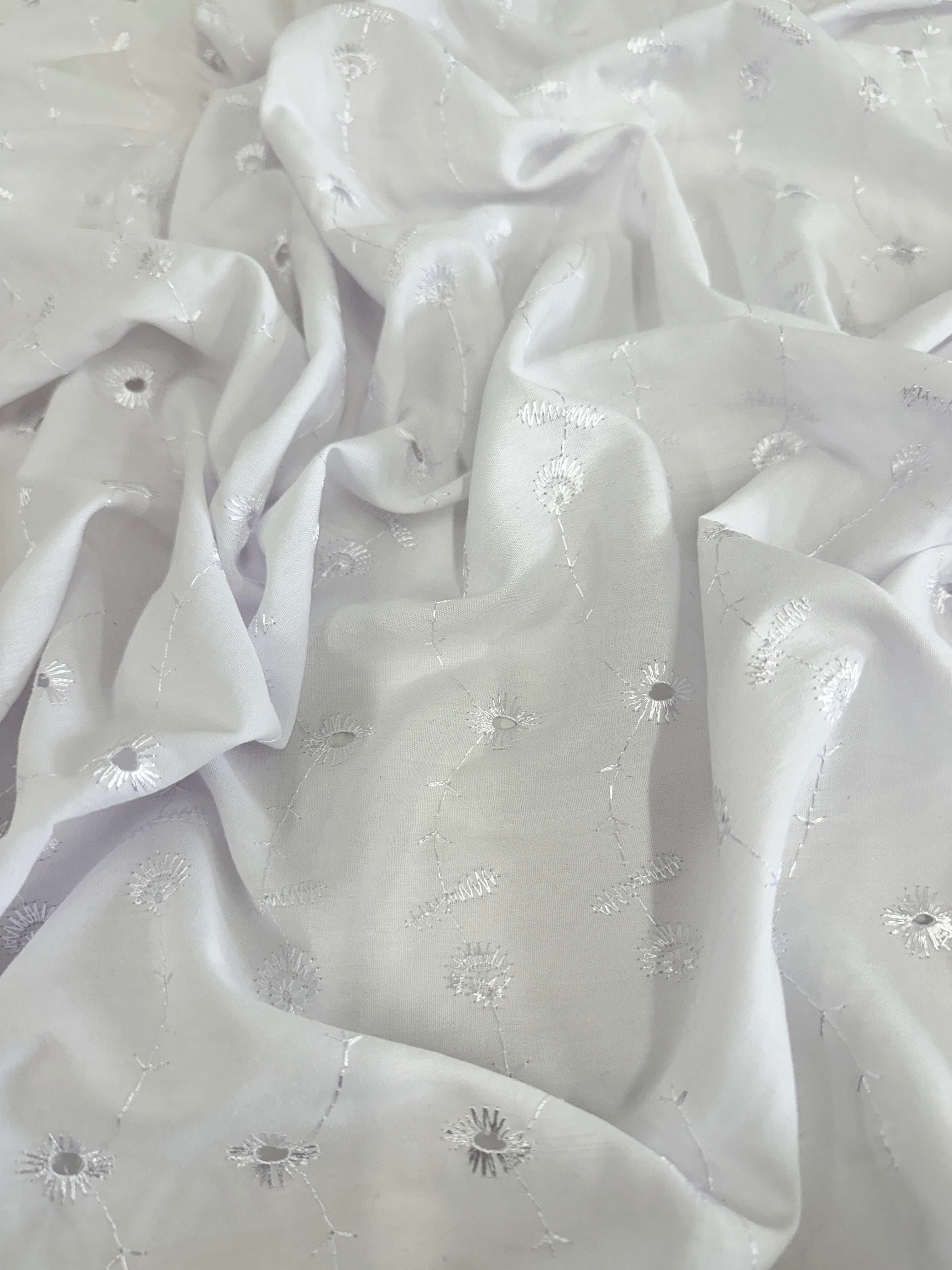 White Dainty cotton fabric with intricate patterns and embellishments