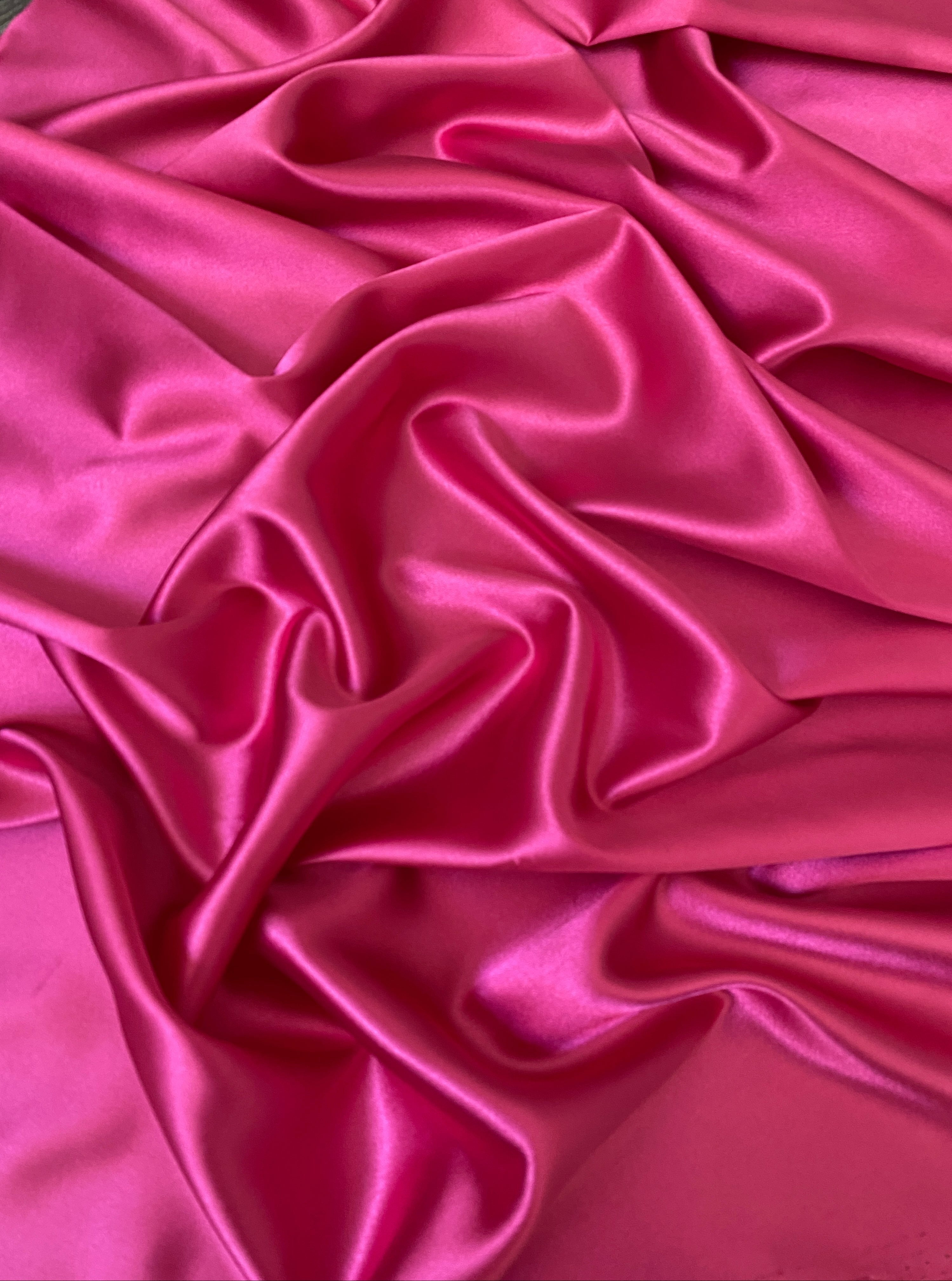 Close-up of pink satin fabric with folds
