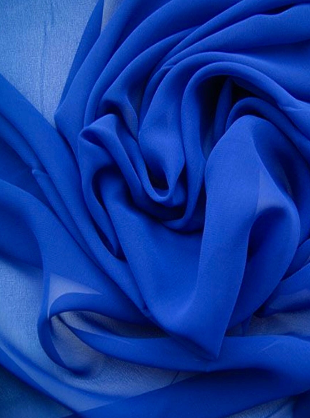 Close-up of blue chiffon fabric with folds on a blue background